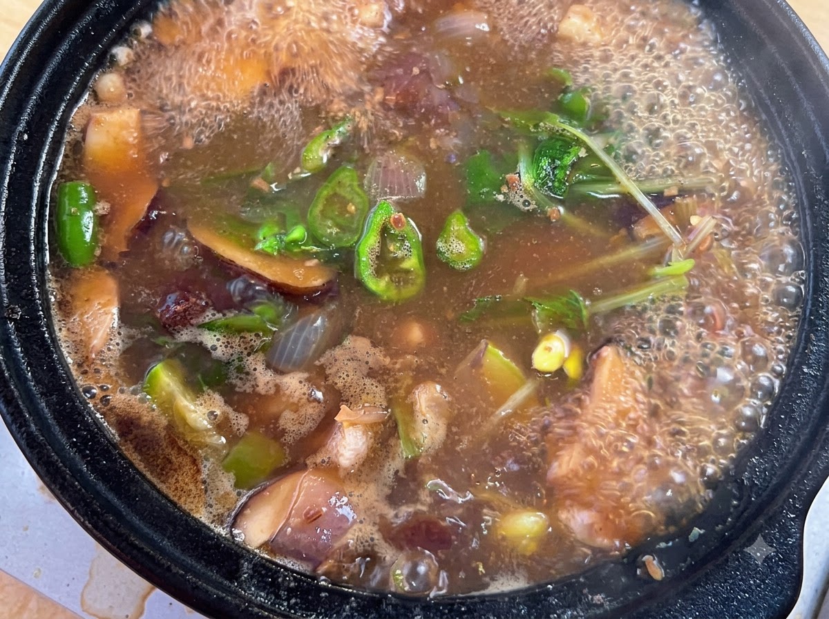 보글보글 끓는 찌개에 소고기 조미료, 고춧가루, 다진 대파를 넣는 모습.