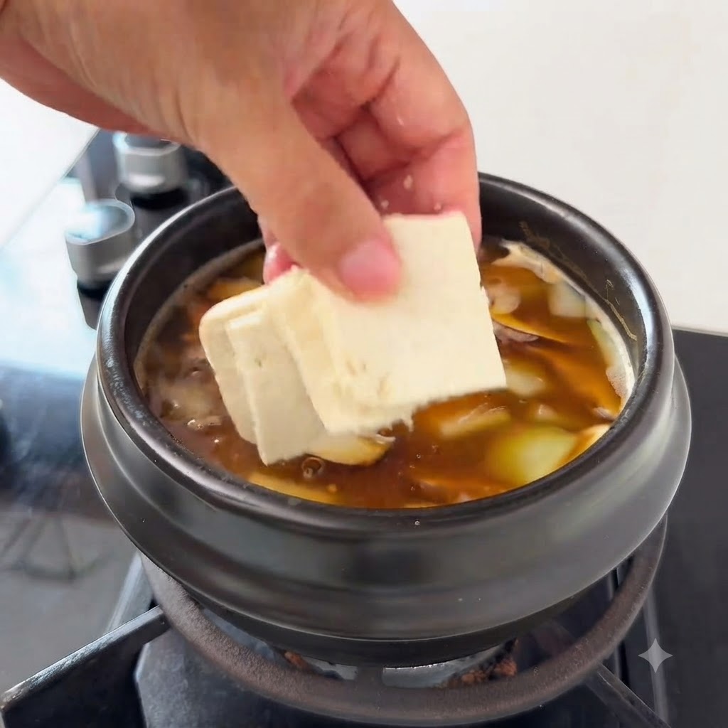 애호박과 팽이버섯이 든 찌개에 두부를 얹는 모습.