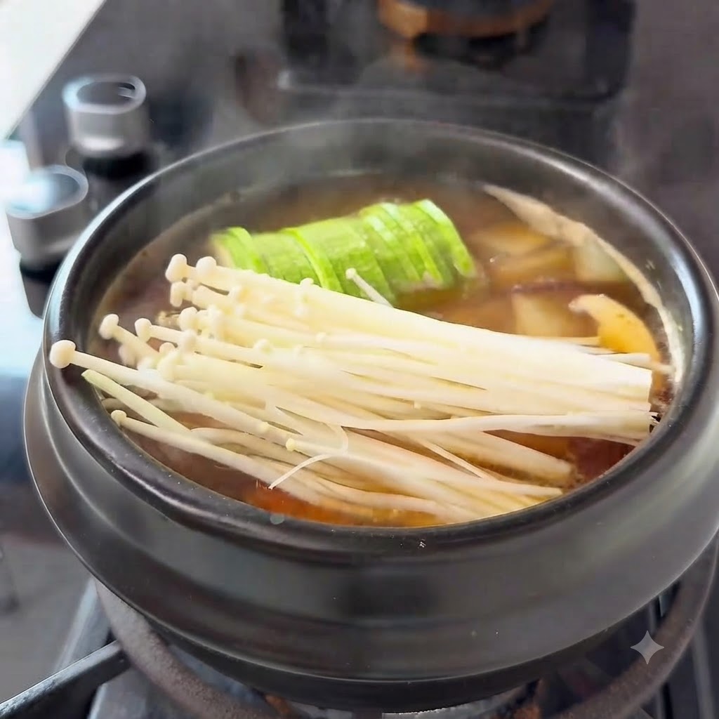 뚝배기 채소 위에 얇게 썬 소고기를 펼쳐 올리는 모습.