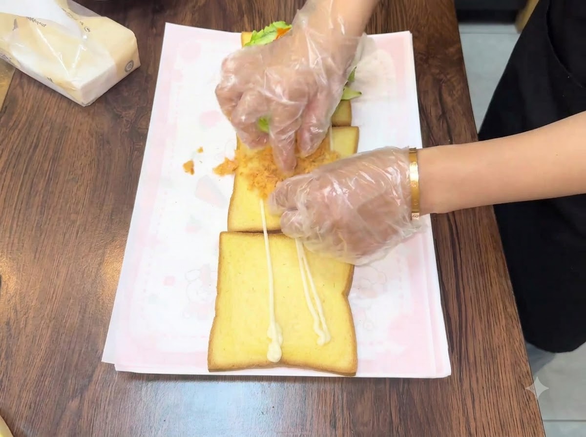 두 번째 빵 조각 위에 부드럽고 황금빛을 띠는 고기 퓌레를 손으로 펴 바르는 모습.