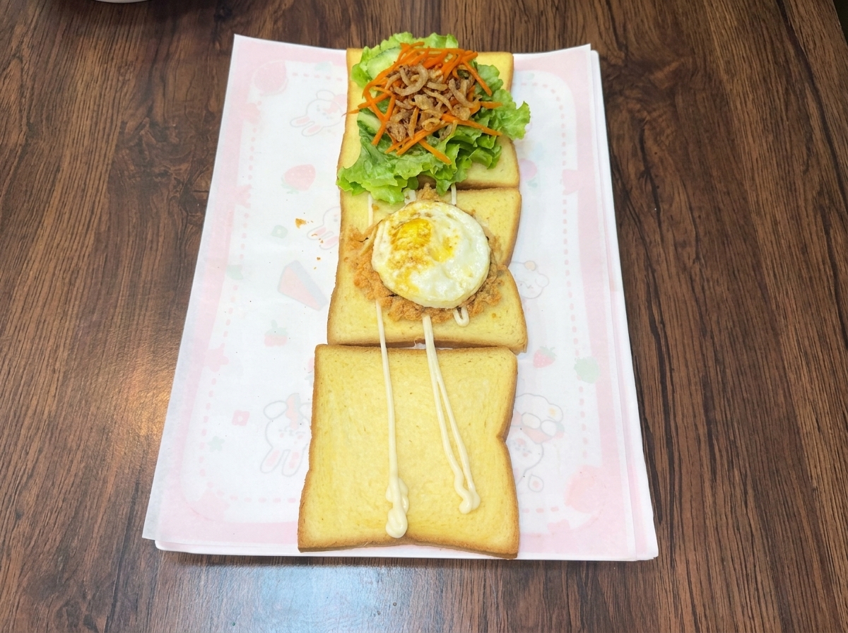 식빵 위 고소한 고기 퓌레와 김가루 층 위에 얹어진 갓 부어낸 달걀프라이.