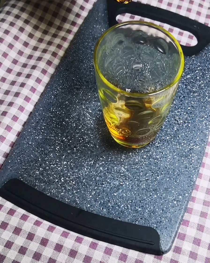 회색 도마 위의 투명한 유리 용기에 진간장을 붓는 모습.
