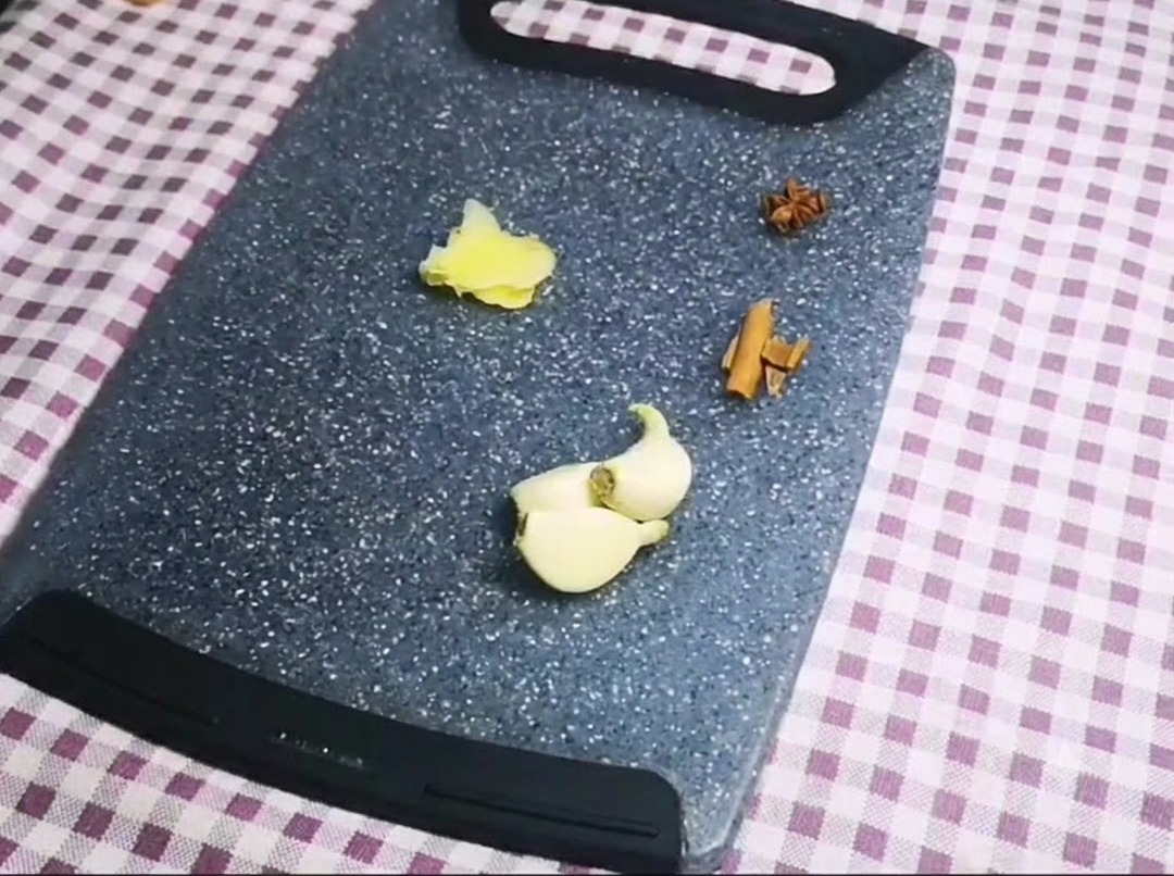 회색 도마 위에 가지런히 놓인 팔각, 시나몬 스틱, 마늘 쪽, 편 썬 생강.
