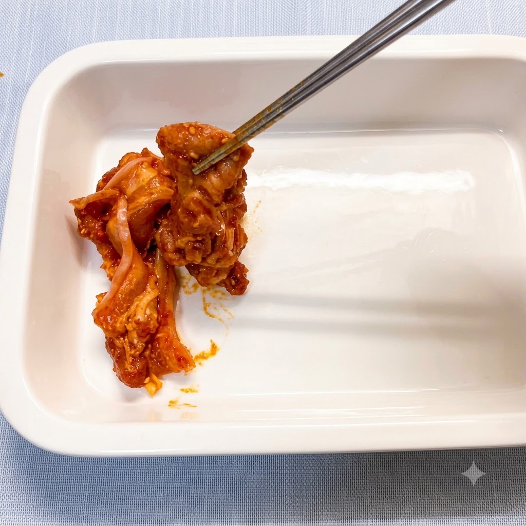 젓가락을 이용해 양념된 삼겹살을 깨끗한 흰색 세라믹 베이킹 디시에 하나씩 올리는 모습.
