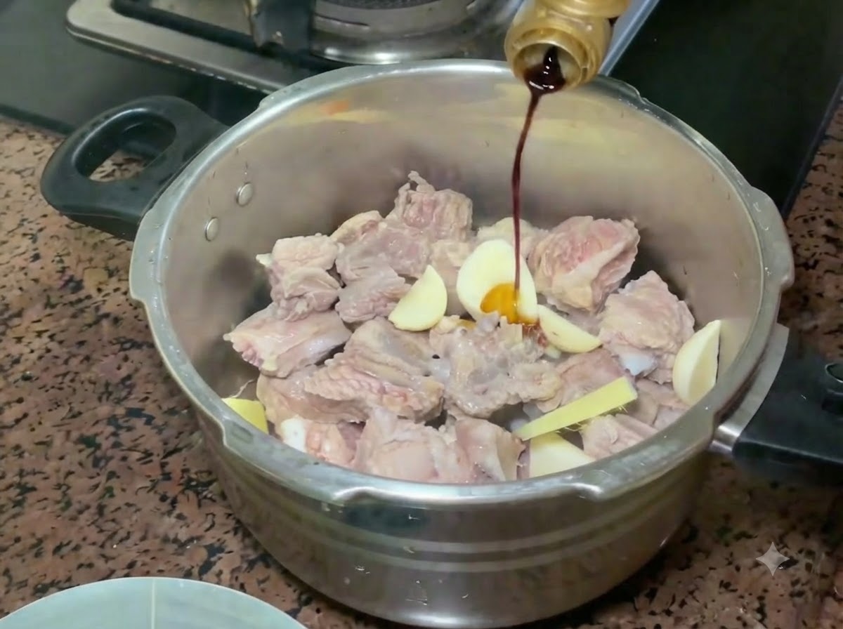 압력솥 안의 돼지갈비와 향신채 위로 병에서 진간장이 부어지고 있는 모습.
