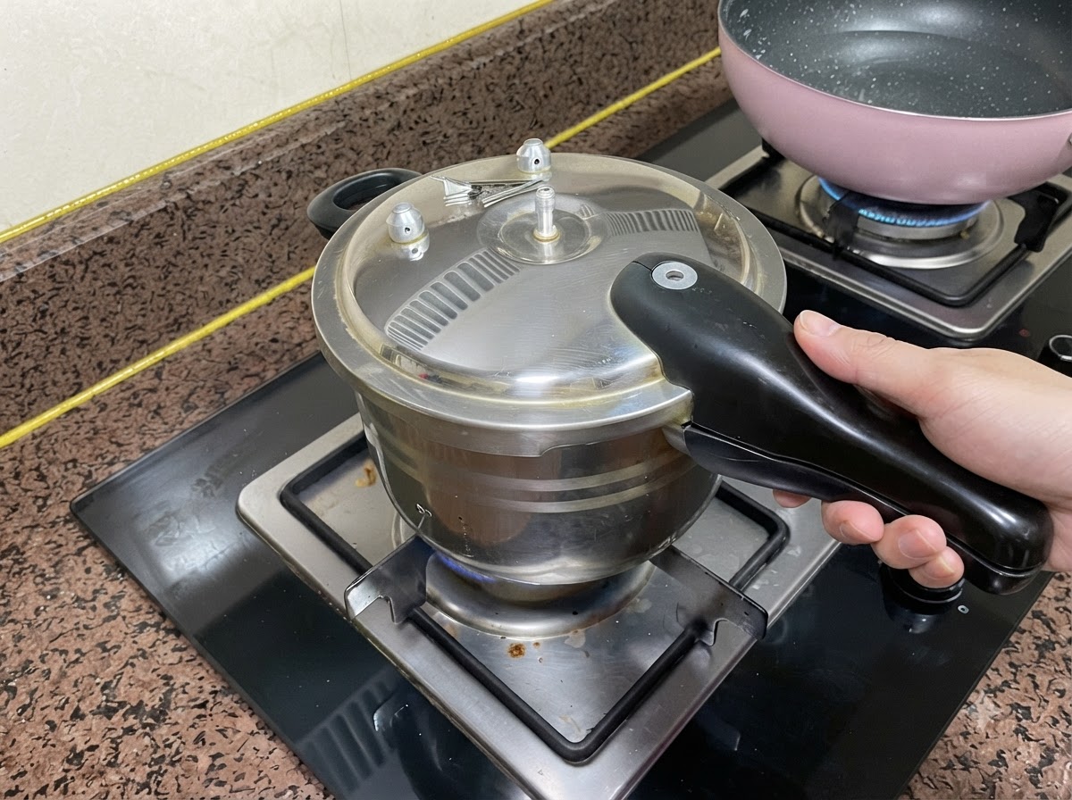 한 손으로 손잡이를 잡고 스토브 버너 위에서 닫힌 압력솥 뚜껑.
