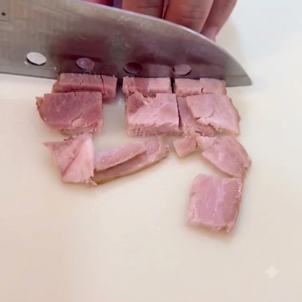 도마 위에서 베이컨을 작은 사각형 모양으로 썰고 있는 모습.