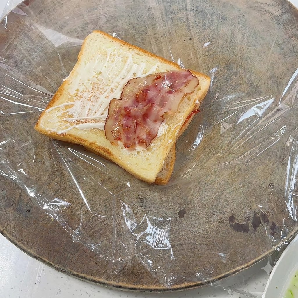 구운 토스트 위에 펼쳐져 올려진 조리된 베이컨 조각들.