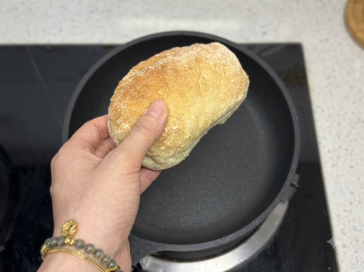 빈 검은색 프라이팬 바로 위에 치아바타 빵을 들고 있는 손.