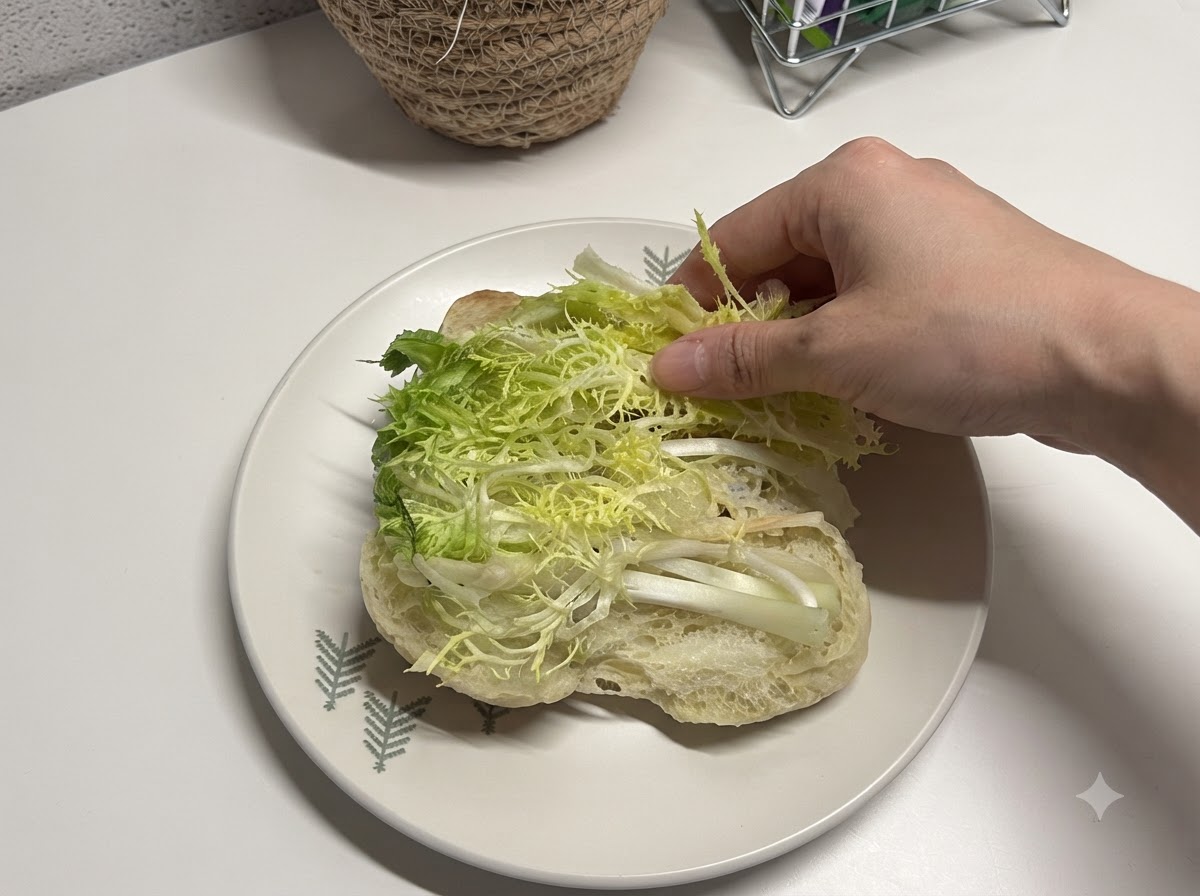 반으로 자른 치아바타 빵 안에 신선한 채썬 상추를 넣는 모습.