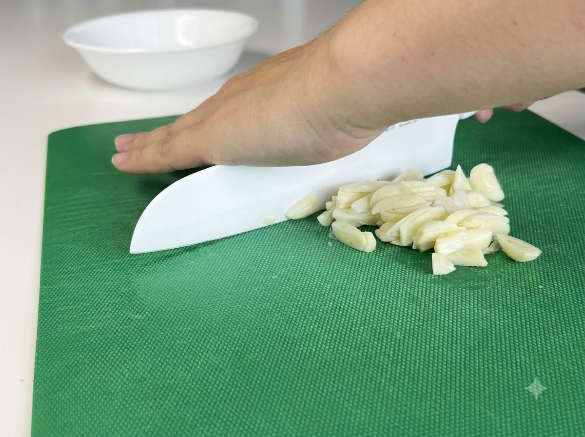 하얀 칼을 사용해 도마 위에서 잘게 다져지는 마늘 쪽들.
