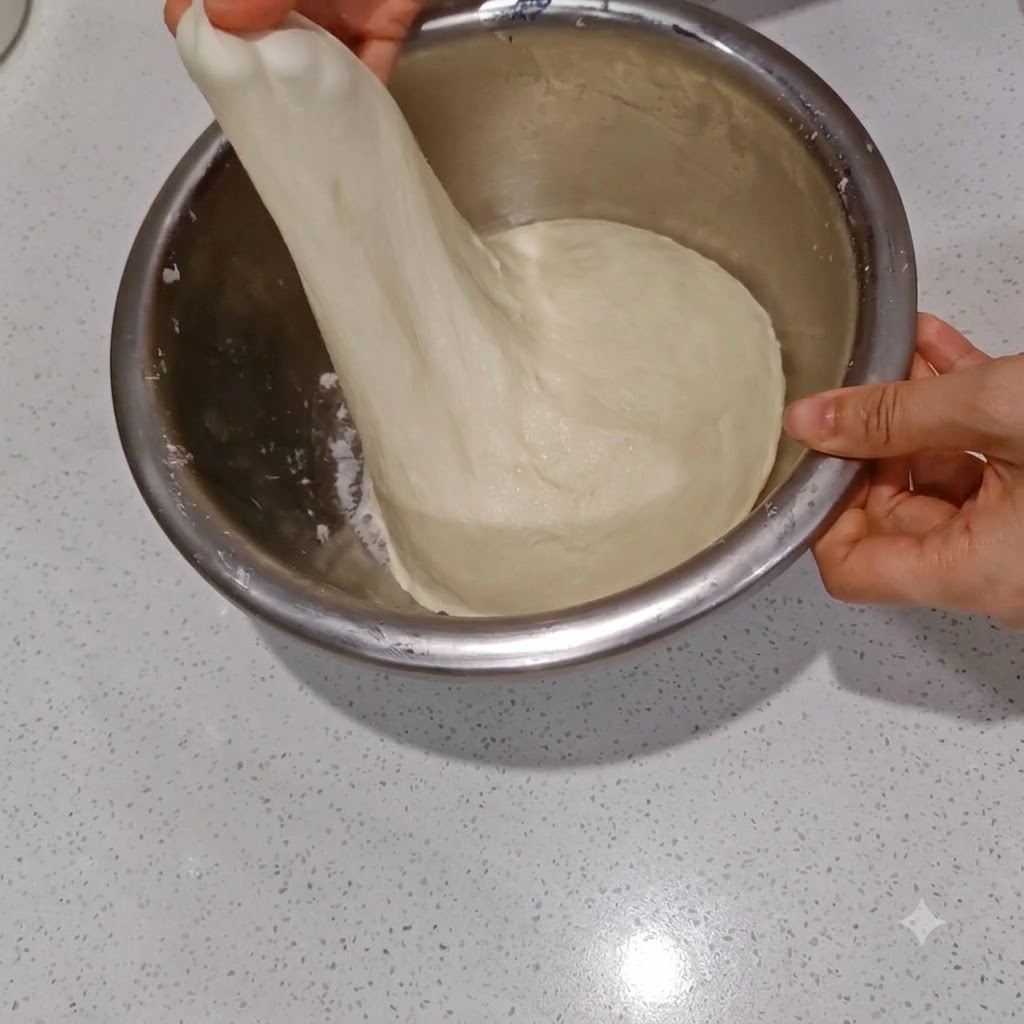 수분이 스며든 반죽을 얇고 반투명한 막이 생기도록 늘려보는 모습.