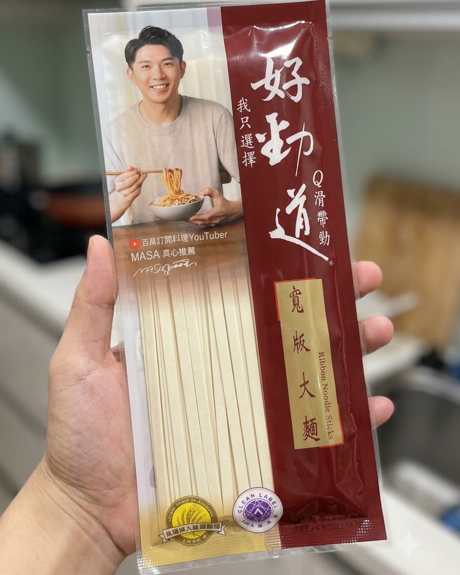 주방 배경 앞에서 하오진다오 넓적 면 건면 패키지를 들고 있는 모습.