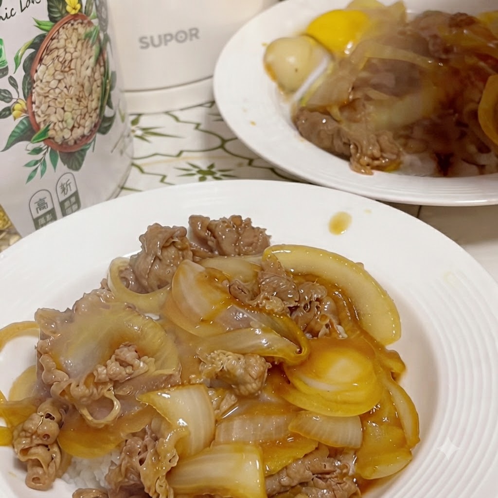 소고기와 밥 중앙에 홈을 파고 달걀 노른자를 얹은 완성된 덮밥 플레이트, 배경에 또 다른 접시가 보이는 모습.