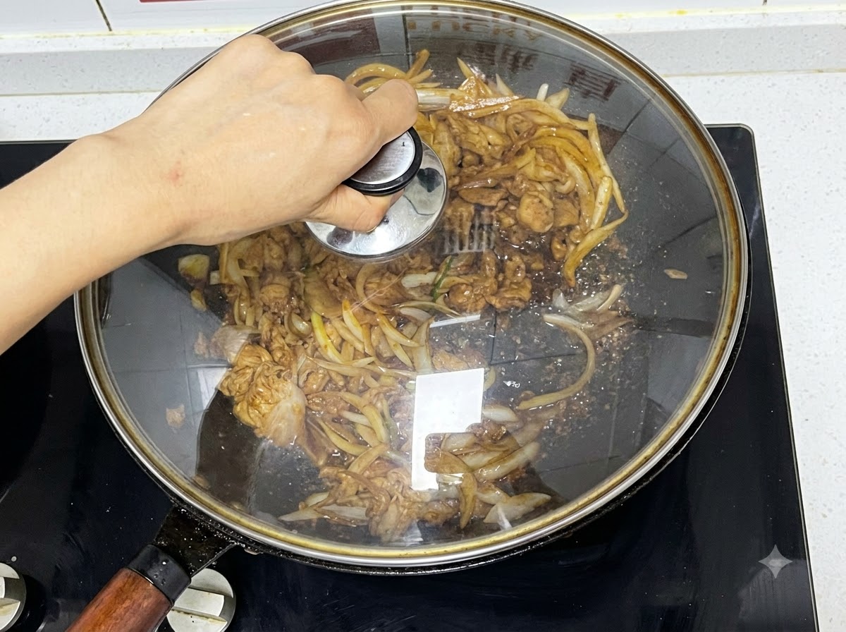 끓고 있는 소고기와 양파가 담긴 웍 위에 유리 뚜껑이 덮이는 모습.