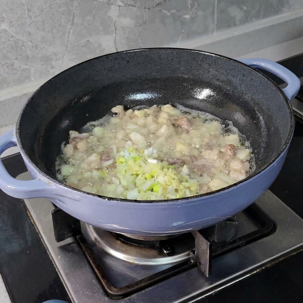 달궈진 팬 속의 지글거리는 고기 위로 곱게 다진 쪽파, 생강, 마늘을 넣고 있는 모습.