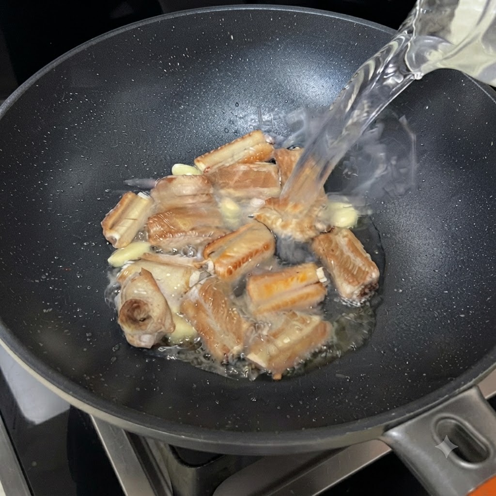 갈비와 마늘이 담긴 지글거리는 팬에 그릇에서 물이 부어지는 모습.