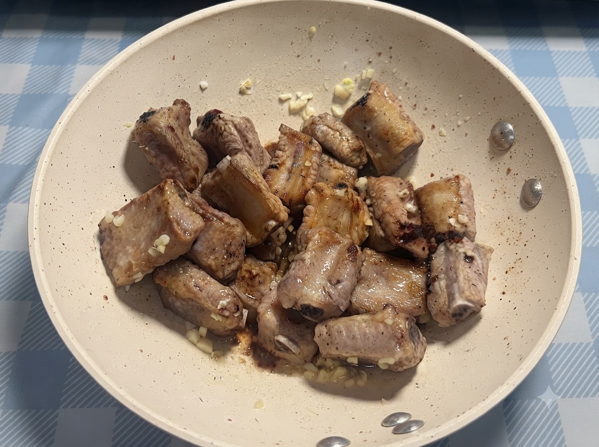 팬프라이한 돼지 갈비 위에 소금 한 꼬집을 직접 뿌리고 있는 모습.