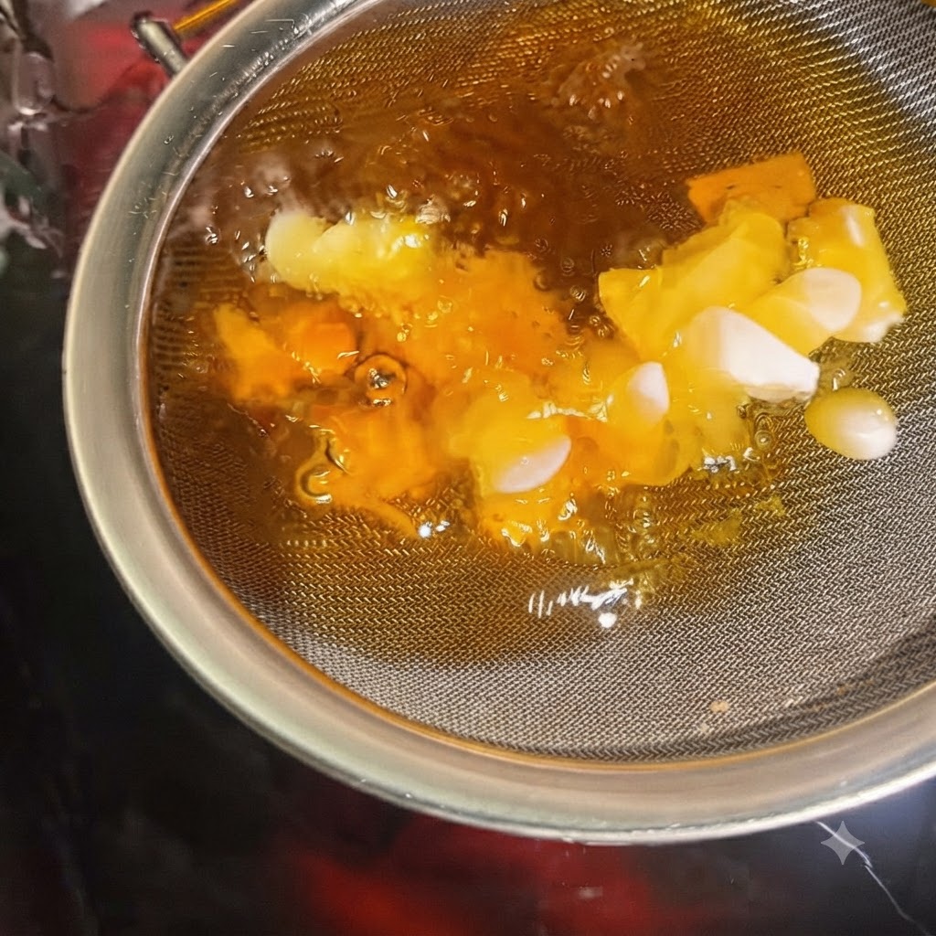 뜨거운 기름에 잠긴 채 소쿠리 안에서 바삭하게 황금빛으로 변하는 마늘 조각들.